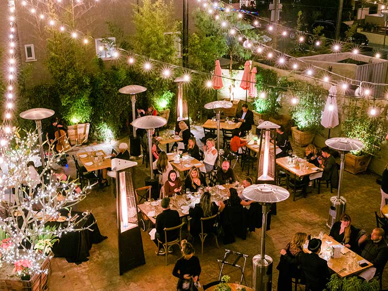 Overhead view of people on a patio at a restaurant with strung lights and heaters